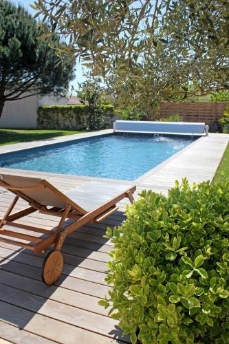 a wooden deck with a pool and a chaise lounge at Le Clos des Romarins in Saint-Palais-sur-Mer