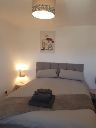een slaapkamer met een groot wit bed en een lamp bij Maria's place (central Ballycastle 3 Bedroom) in Ballycastle