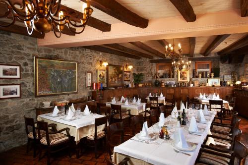 un restaurante con mesas y sillas blancas y una lámpara de araña en Guesthouse Domacija Sajna en Sežana