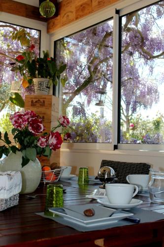 a table with dishes and flowers on it with two windows at Le Clos des Romarins in Saint-Palais-sur-Mer