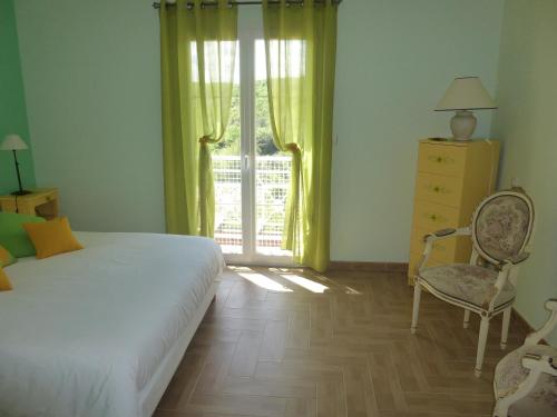 a bedroom with a bed and a chair and a window at Domaine de Flo ADULT a partir de 16 ans in Saint-Jean-de-la-Blaquière
