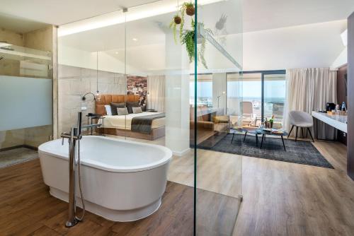 a bathroom with a bath tub and a bedroom at AP Maria Nova Lounge - Adults Friendly in Tavira