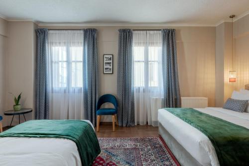 a hotel room with two beds and two windows at Paeonia Arachova in Arachova