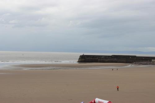 a person standing on a beach near the ocean at Bayside Guest House in Porthcawl