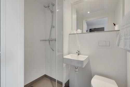 La salle de bains blanche est pourvue d'un lavabo et d'une douche. dans l'établissement initial by balladins Blois, à Blois