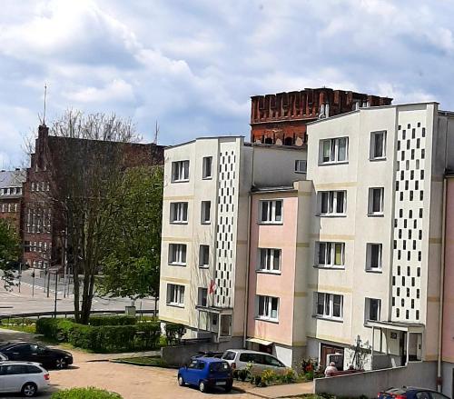 biały budynek z samochodami zaparkowanymi na parkingu w obiekcie Old Town Apartment w mieście Malbork