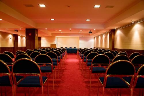 an empty hall with chairs and a screen and a red carpet at Pharae Palace in Kalamata