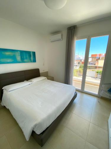 a bedroom with a large bed and a large window at Vespucci Apartments Torre Lapillo in Torre Lapillo