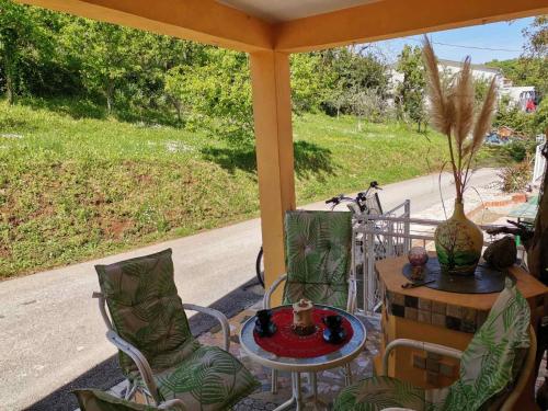 a porch with a table and chairs and a table and a vase at Apartman SIRENA in Pićan