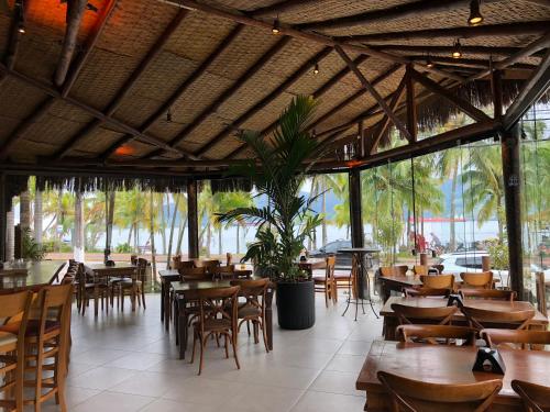 um restaurante com mesas e cadeiras de madeira e um tecto grande em Suite 4101 Ilhaflat em Ilhabela