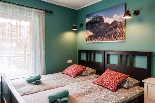 Schlafzimmer mit einem Bett mit roten Kissen und einem Fenster in der Unterkunft Apartament Bajkowy in Zakopane