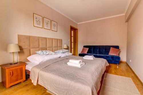 sypialnia z dużym łóżkiem i niebieską kanapą w obiekcie Krynica Apartamenty Centrum Deptak 45 w mieście Krynica Zdrój