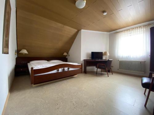 a bedroom with a bed and a desk and a window at Parkhotel in Rottweil