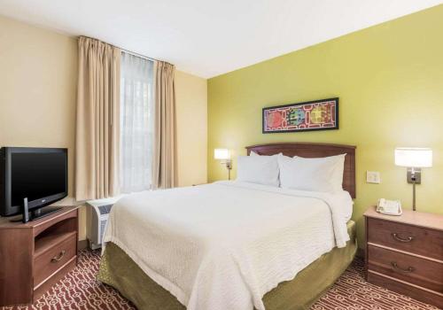 a hotel room with a bed and a flat screen tv at Birch Hills Suites - Blue Ash in Blue Ash