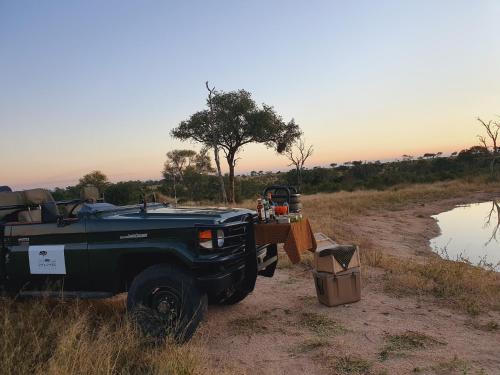 a truck parked on a dirt road next to a river at Umkumbe Bush Lodge - Luxury Tented Camp in Sabi Sand Game Reserve