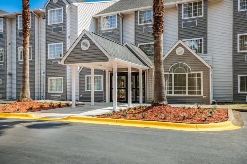 a building with palm trees in front of a street at Sleep Inn & Suites Tallahassee - Capitol in Tallahassee