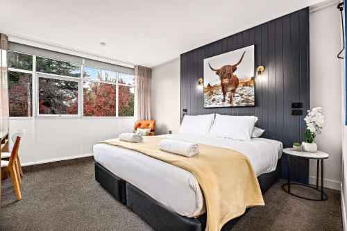 Un dormitorio con una cama grande con una foto de una vaca en City Centre Motel Armidale en Armidale