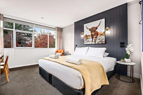 a bedroom with a large bed with a picture of a cow at City Centre Motel Armidale in Armidale