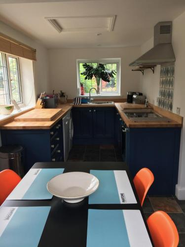 a kitchen with blue cabinets and a table with orange chairs at Wartling Place Country House in Wartling