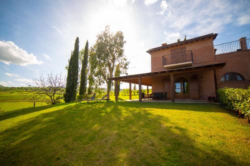 ein Haus auf einem Grasfeld mit der Sonne dahinter in der Unterkunft Terra Antica - Resort, Winery & SPA in Montepulciano