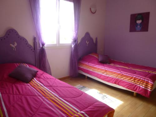 two beds in a room with pink sheets and a window at Villa Le Tournesol in Saint-Jean-de-la-Blaquière