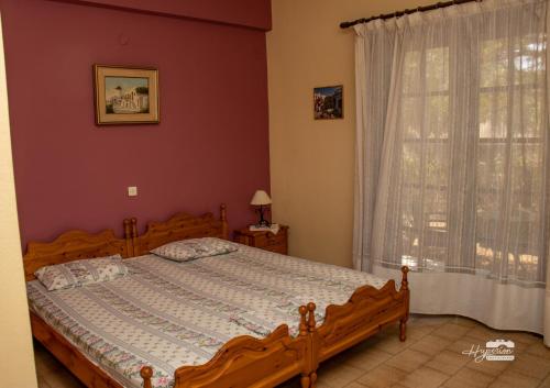 a bedroom with a wooden bed and a window at Eirini Kasimiotou Apartments in Agios Andreas
