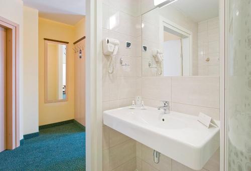 a white bathroom with a sink and a shower at Hotel Wodnik in Slok