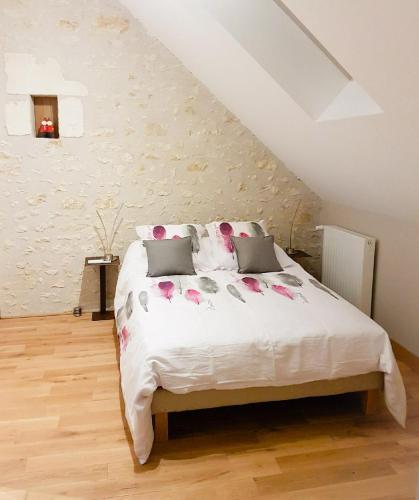 - une chambre avec un lit blanc orné de fleurs roses dans l'établissement Gîte Les Nymphéas, à Épeigné-les-Bois