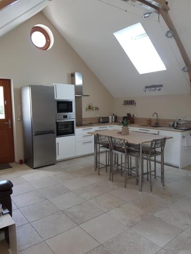 une cuisine avec une table avec des chaises et un réfrigérateur dans l'établissement Gîte Les Nymphéas, à Épeigné-les-Bois