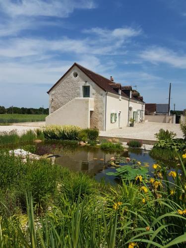 un edificio con un estanque delante de él en Gîte Les Nymphéas, en Épeigné-les-Bois