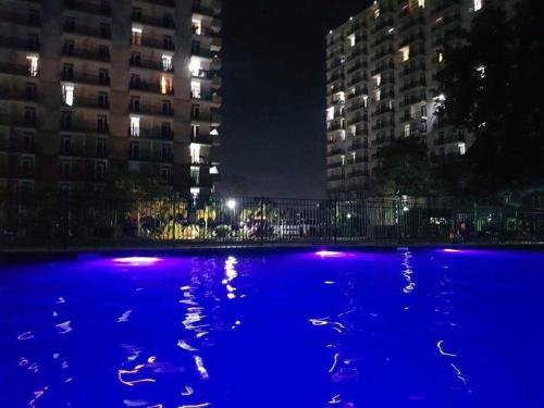 a large pool of blue water at night with buildings at HPH Staycation - Saekyung 956 Condo in Mactan