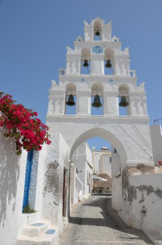 a white building with a bell tower with flowers at Vineyards Hill Villa in Megalokhori