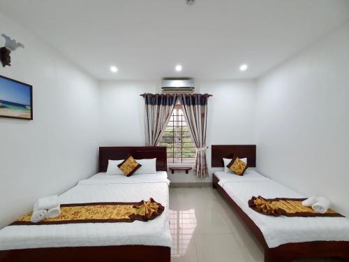 two beds in a room with a window at Khách sạn Thái Bình in Con Dao