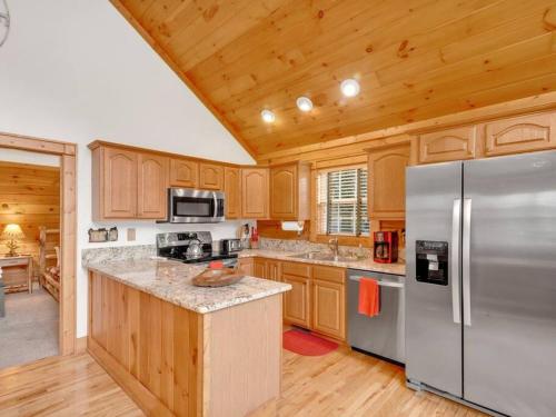 a kitchen with wooden cabinets and a stainless steel refrigerator at Soco Serene Cabin in the Heart of Maggie Valley in Maggie Valley