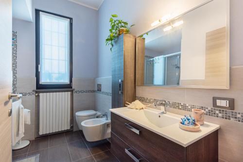 uma casa de banho com um lavatório, um WC e um espelho. em Villetta Belvedere em Piacenza
