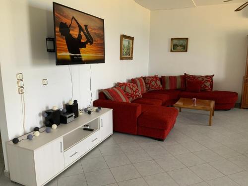 a living room with a red couch and a table at Xenia Apartment in Kokkari