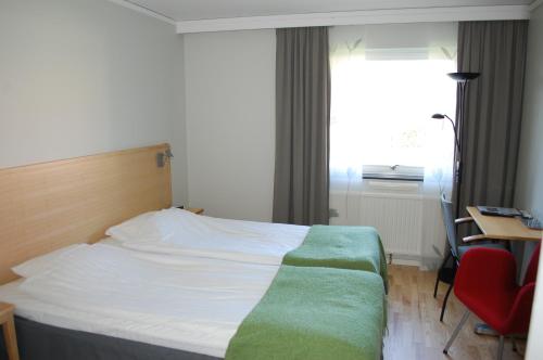 a bedroom with a bed and a desk and a window at Allégården Kastlösa Hotell in Kastlösa