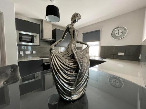 metalowy posąg kobiety w kuchni w obiekcie Apartments No. 19 w mieście Portpatrick