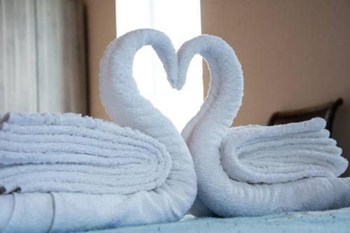 two towels shaped like swans sitting on a bed at Pulchra Campis,Private Pool,Wifi,Parking in Nerokoúros