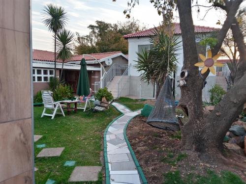 a garden with a stone walkway next to a tree at Dante Guest house in Alberton