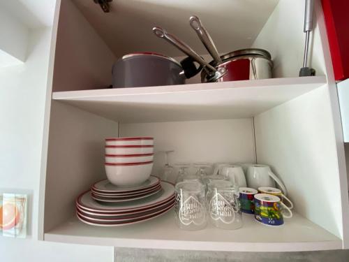 a cupboard with plates and dishes in it at Studio au Coeur du Village avec terrasse et parking proche de Pamiers in Verniolle
