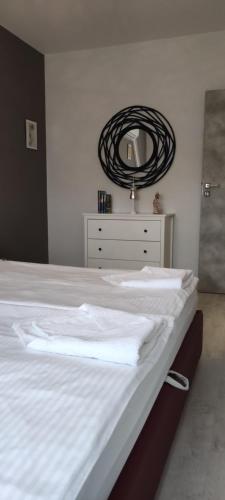 a bedroom with a white bed with a mirror at IKON apartman in Hajdúszoboszló