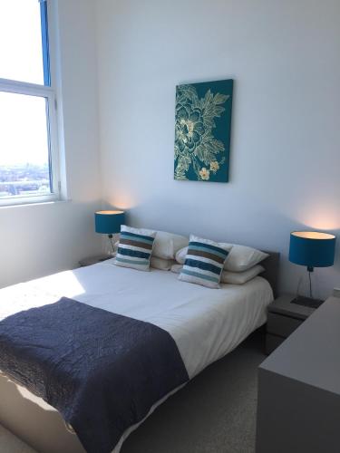 een slaapkamer met een groot bed en 2 blauwe lampen bij Sky View Apartment with Terrace in Bedford