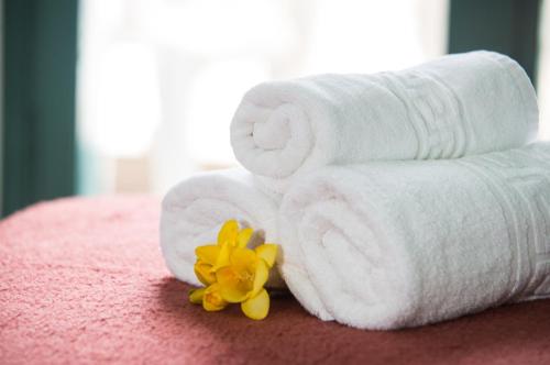 a pile of towels and a yellow flower on a bed at Theoni Apartments in Malia