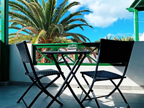 dwa krzesła i stół na balkonie z palmą w obiekcie Apartamento VISTAenRELAX w Puerto del Carmen