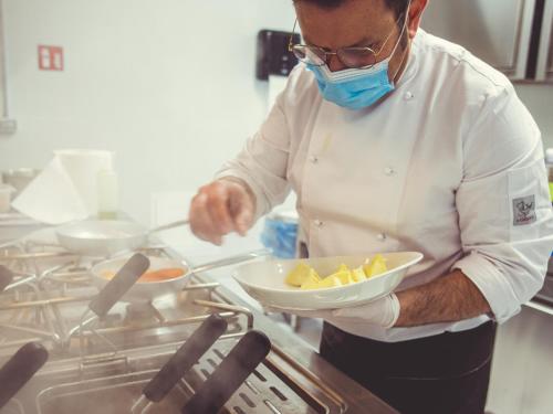 a chef wearing a mask holding a bowl of food at Modica Boutique Hotel in Modica