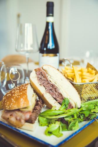 a sandwich and french fries on a plate with a bottle of wine at Modica Boutique Hotel in Modica