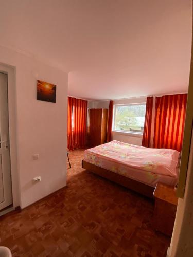 una camera con letto e finestra con tende rosse di vila Monski ad Azuga