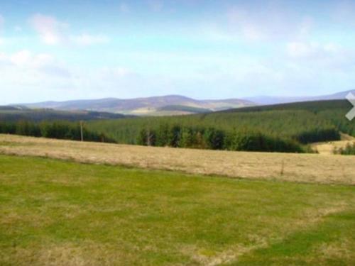 ein Grasfeld mit Bergen im Hintergrund in der Unterkunft Ben Rinnes Lodge Glenlivet Highlands in Auchnastank