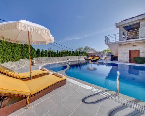 a pool with two lounge chairs and an umbrella at Villa Ilijana in Tivat